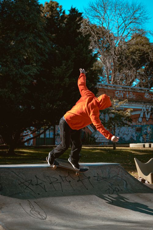 Free A skateboarder in a bright orange hoodie performs a trick at a skate park in Buenos Aires. Stock Photo