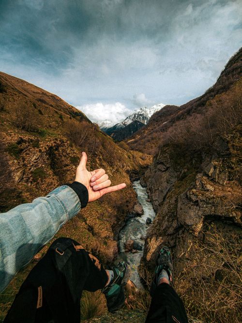 Free Person hiking in scenic mountain landscape, showing thumb gesture. Perfect for travel adventure themes. Stock Photo