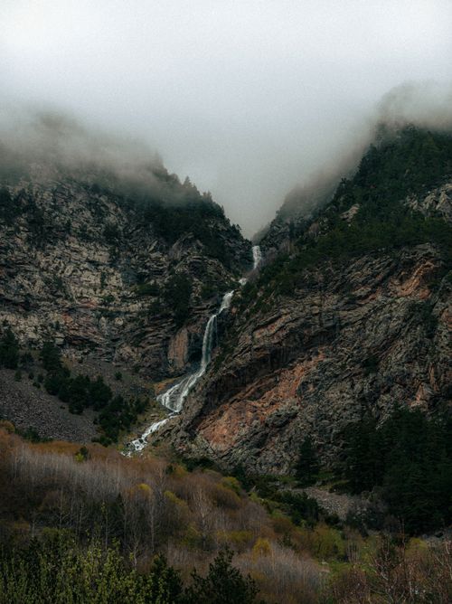 Free Beautiful misty waterfall cascading down a rugged mountain landscape. Stock Photo