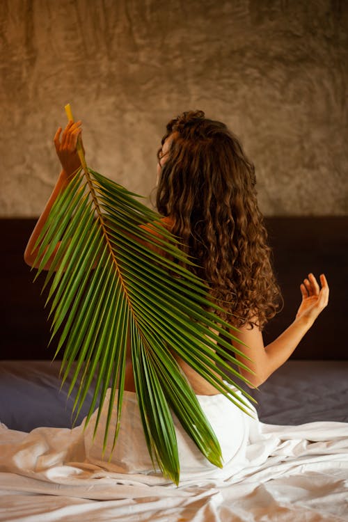Free Woman in White Skirt Holding Green Palm Leaf Behind Back Stock Photo