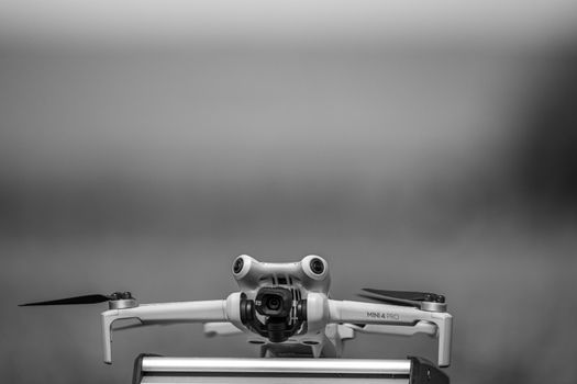 Black and white close-up photo of a drone outdoors, ready for takeoff.