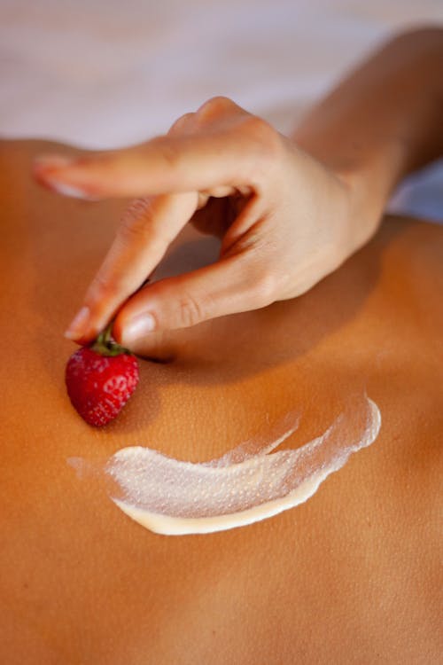 Person Holding Red Strawberry on Woman's Belly