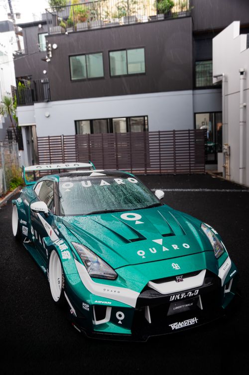 Free Green Nissan sports car with a spoiler parked in a modern Tokyo street setting. Stock Photo