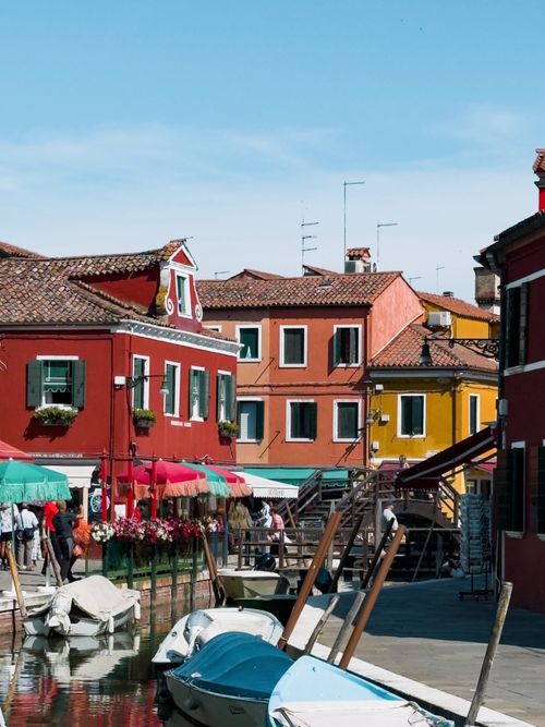 Free Vibrant houses along a canal in Burano, Venice with boats and a clear sky. Stock Photo