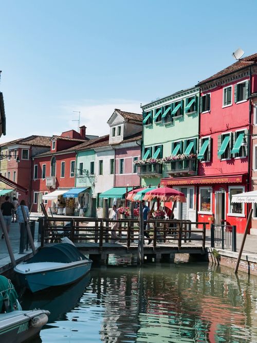 Free Vibrant Burano canal scene featuring colorful houses with boats and reflections. Stock Photo