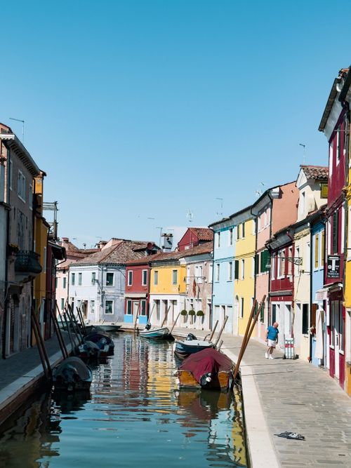 Free Vibrant houses along a serene canal in Burano, Italy under a clear blue sky. Stock Photo