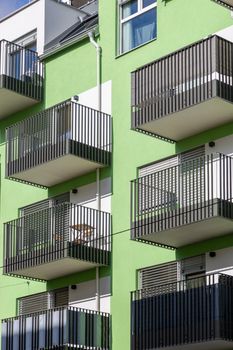 Contemporary apartment building with green facade and multiple balconies under daytime light.