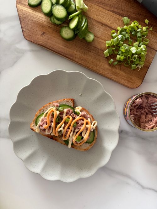 Free Delicious open-faced tuna sandwich topped with cucumbers and green onions on a marble countertop. Stock Photo