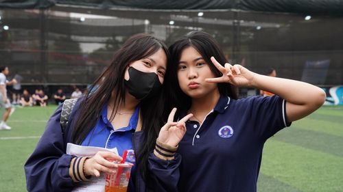 Free Two teenage girls in school uniforms make peace signs outdoors, capturing a joyful moment of friendship and youth. Stock Photo