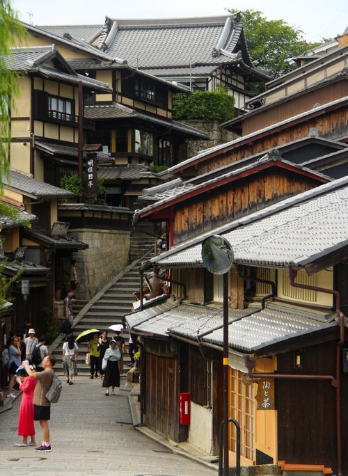 Free Tourists explore the historic streets of Kyoto, Japan, capturing traditional architecture. Stock Photo