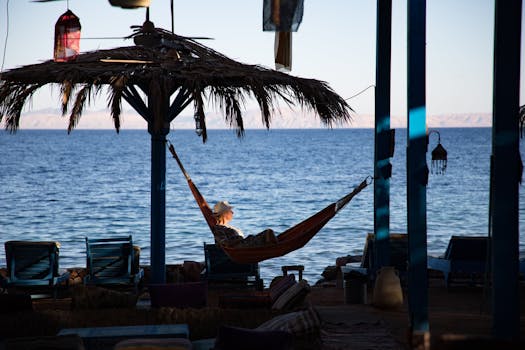 黄昏时分，女人在海边的吊床上享受休闲时光