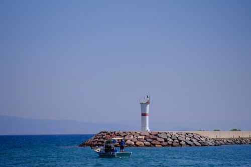 Free Fisherman in boat by a lighthouse on the Aegean Sea in İzmir, Türkiye. Stock Photo