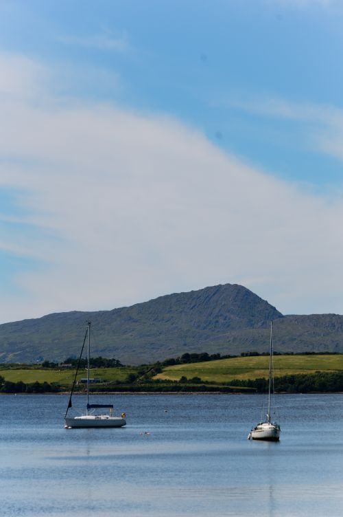 Free Tranquil scene of sailboats on Bantry Bay with a mountain backdrop on a clear summer day. Stock Photo