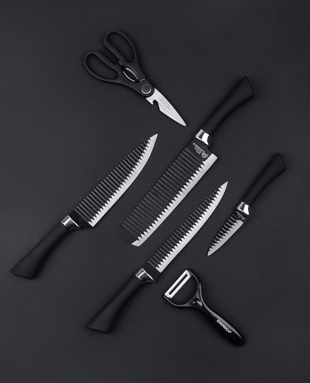 As assortment of kitchen knives flat laid on a neutral background