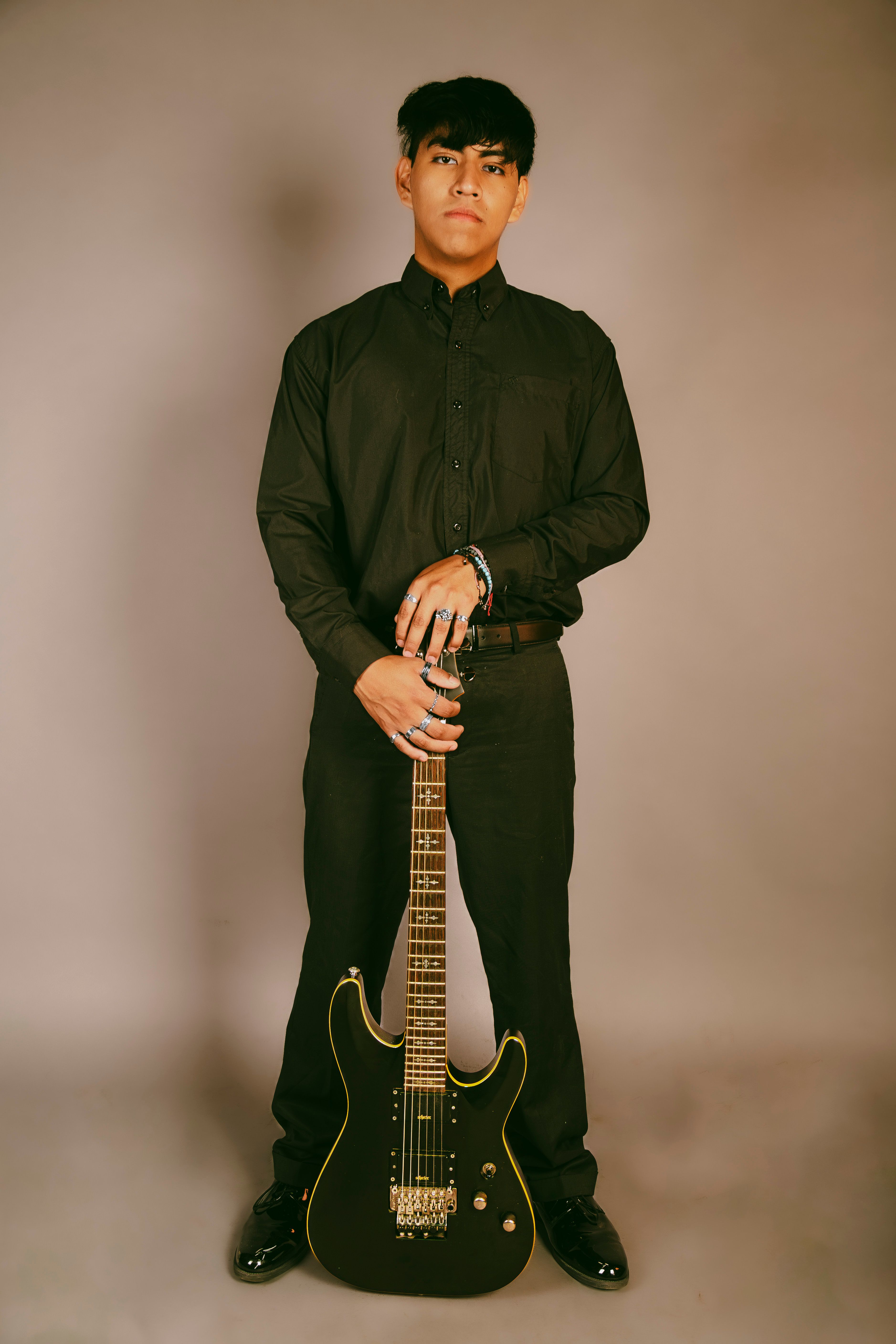 Portrait of a young man holding an electric guitar in a studio setting.
