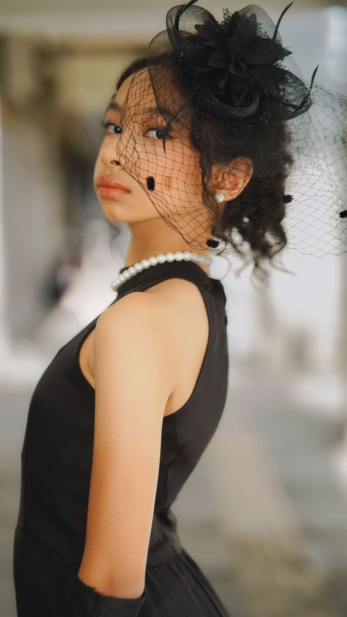 Free Profile of a stylish woman in black attire with pearl necklace and veil hat. Stock Photo