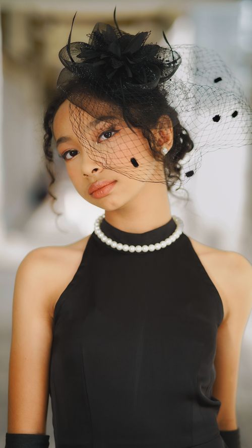 Free Chic portrait of a woman in a black dress, wearing pearls and an elegant hat. Stock Photo