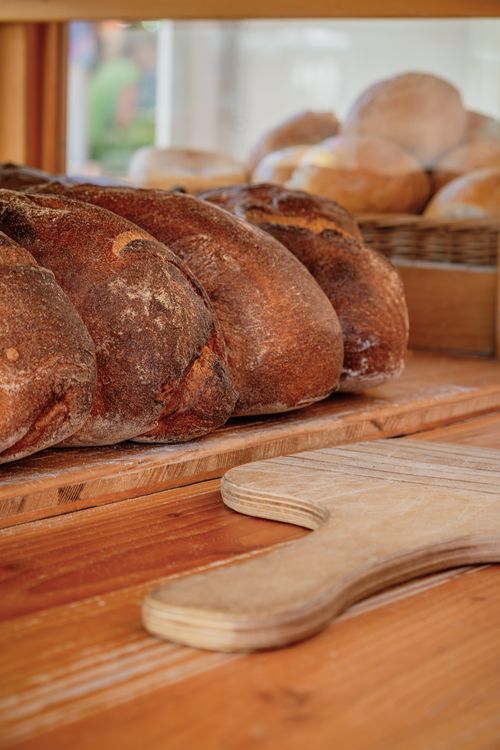 Free Close-up of freshly baked bread loaves on a wooden table in a bakery setting. Stock Photo