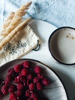 Elevate your breakfast with fresh raspberries and coffee on a rustic table setting.
