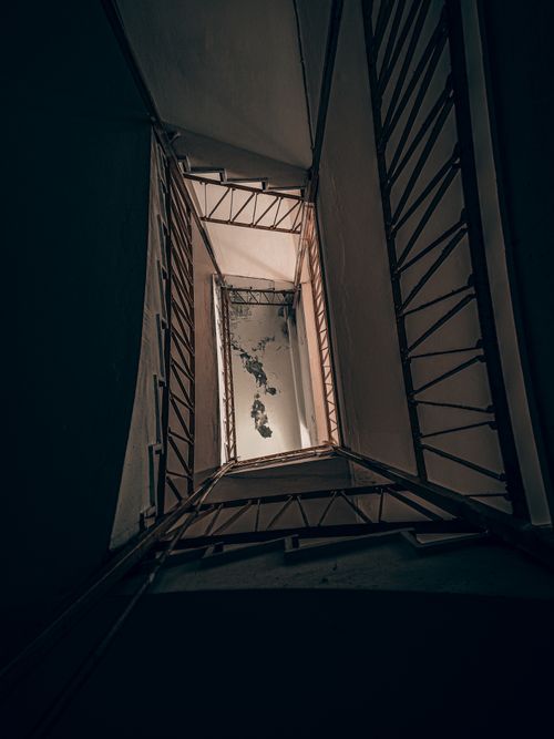 Free Low angle of metal stair railing inside shabby dark industrial building with high ceiling Stock Photo