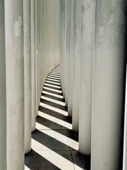 Artistic play of light and shadows between tall columns in Luxembourg.