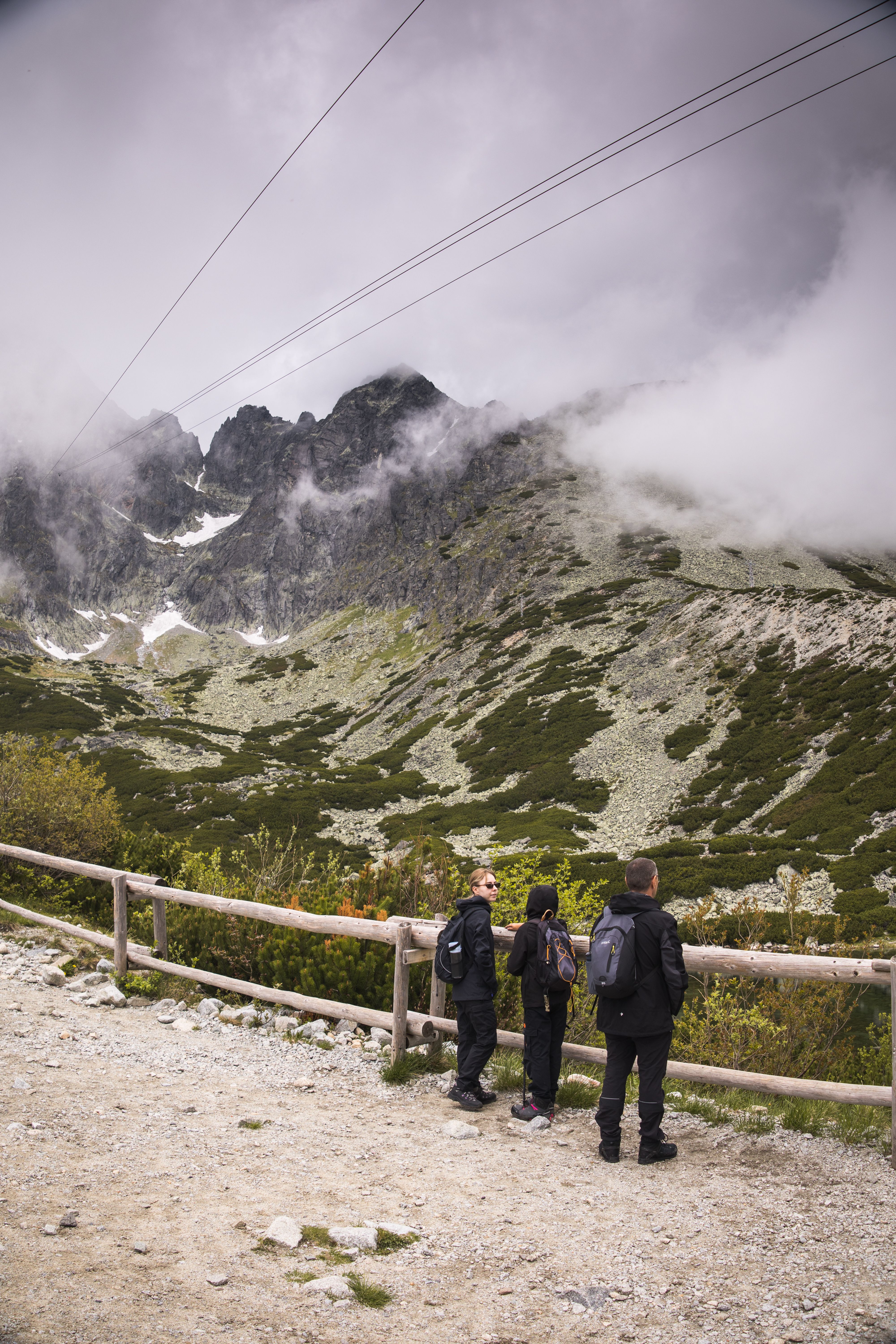 Three hikers admire the misty High Tatras landscape in Slovakia's Presov region.