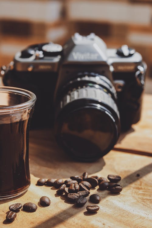 Black and Silver Nikon Dslr Camera Beside Glass Full of Coffee