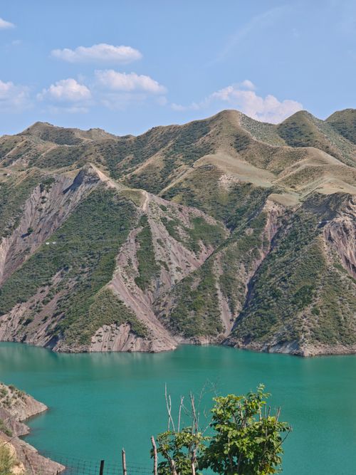 Free Panoramic view of rugged mountains surrounding a serene turquoise lake under a clear blue sky. Stock Photo