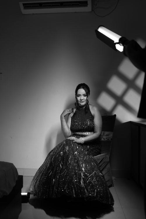 Free Black and white portrait of a woman elegantly seated, wearing a sparkling evening gown indoors. Stock Photo