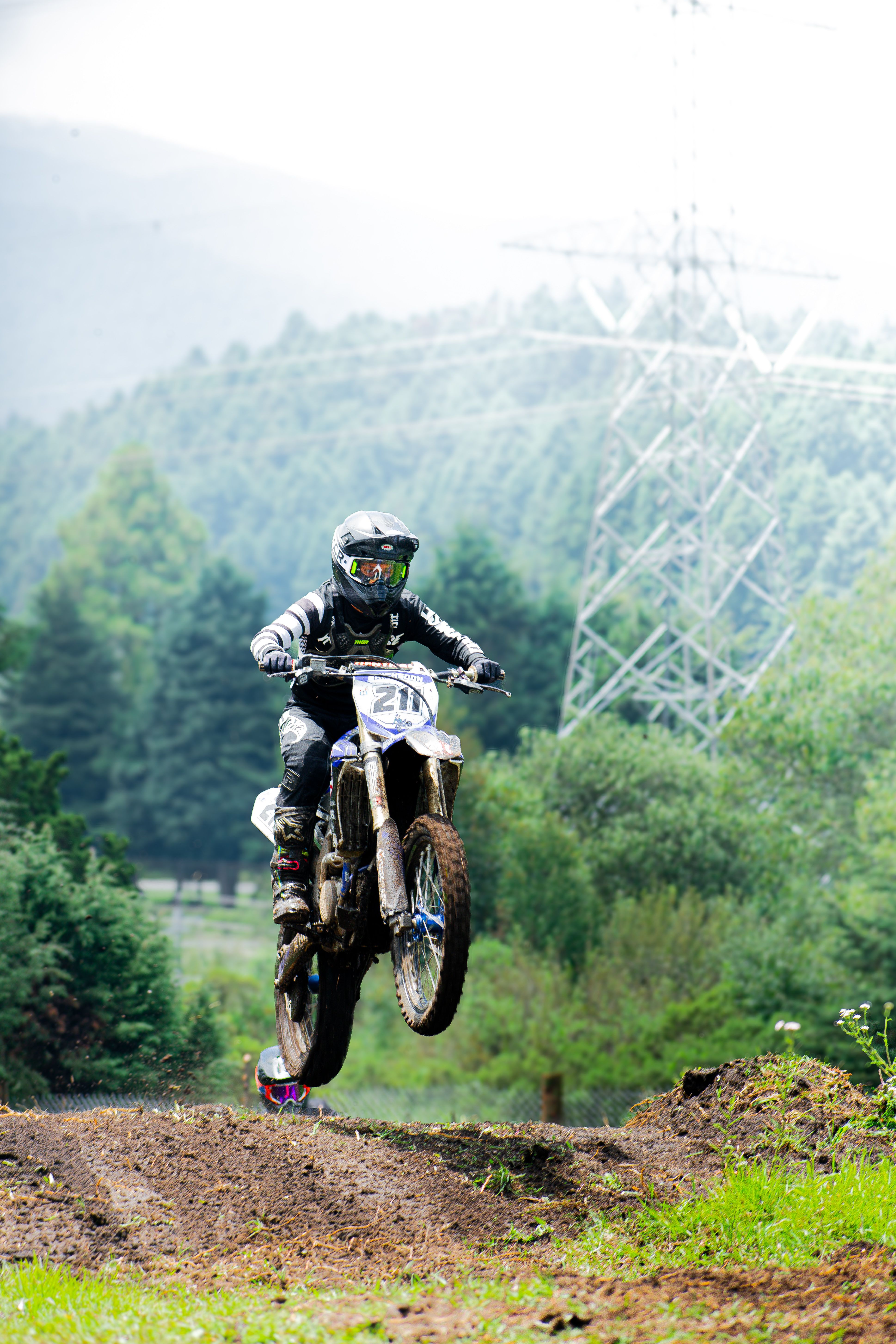 Motorcyclist performs a high jump during an off-road race in the lush forests of Mexico.