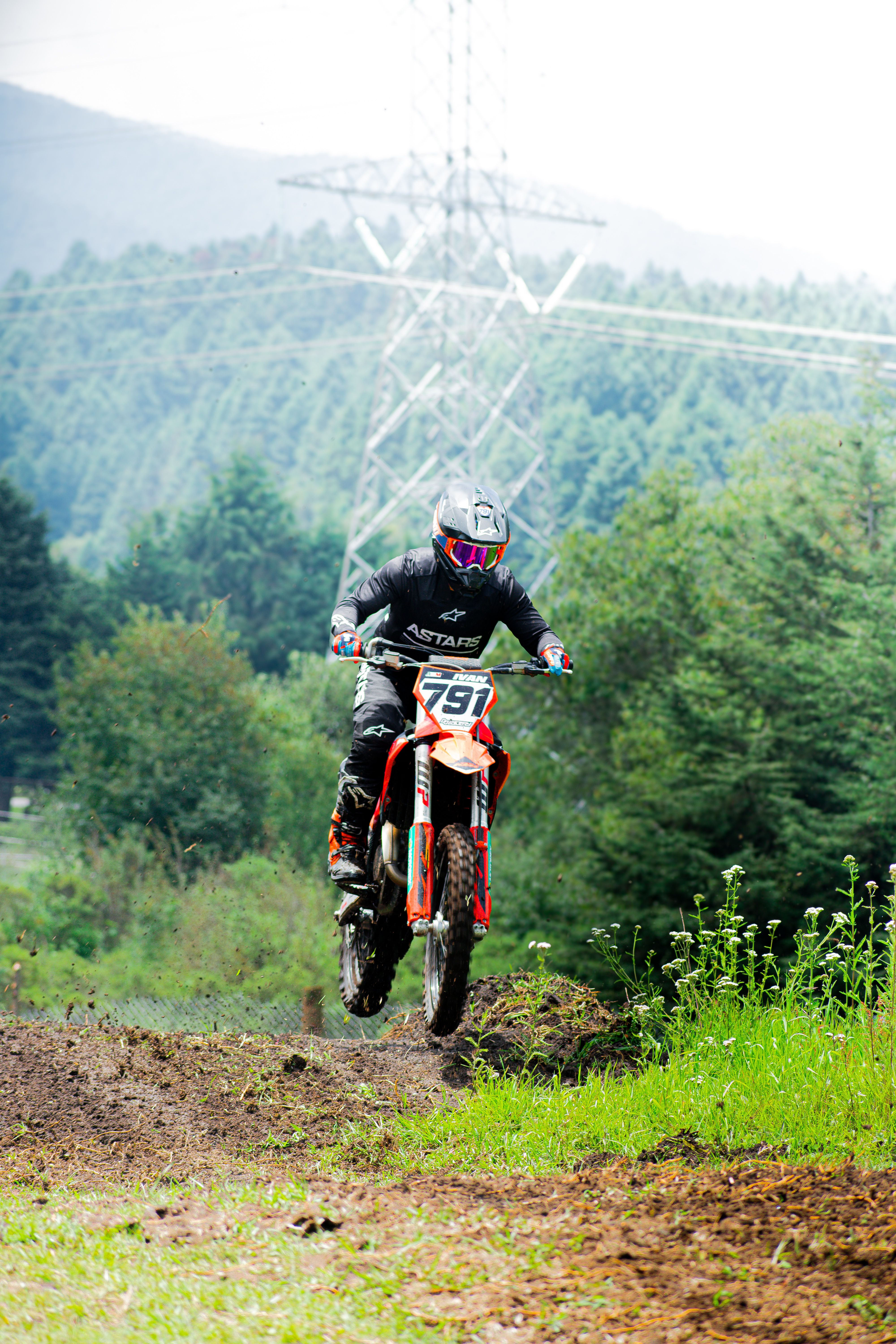 Motorcyclist racing off-road in lush greenery, showcasing speed and thrill.