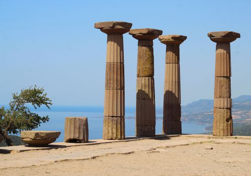Ancient columns of the Temple of Athena in Assos, Türkiye with stunning Aegean Sea view.