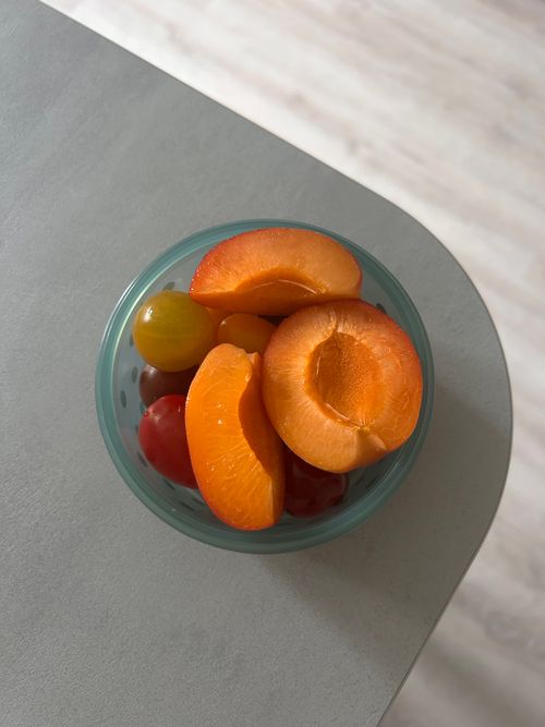 Free Top view of fresh apricots and cherry tomatoes in a glass bowl on a table. Stock Photo