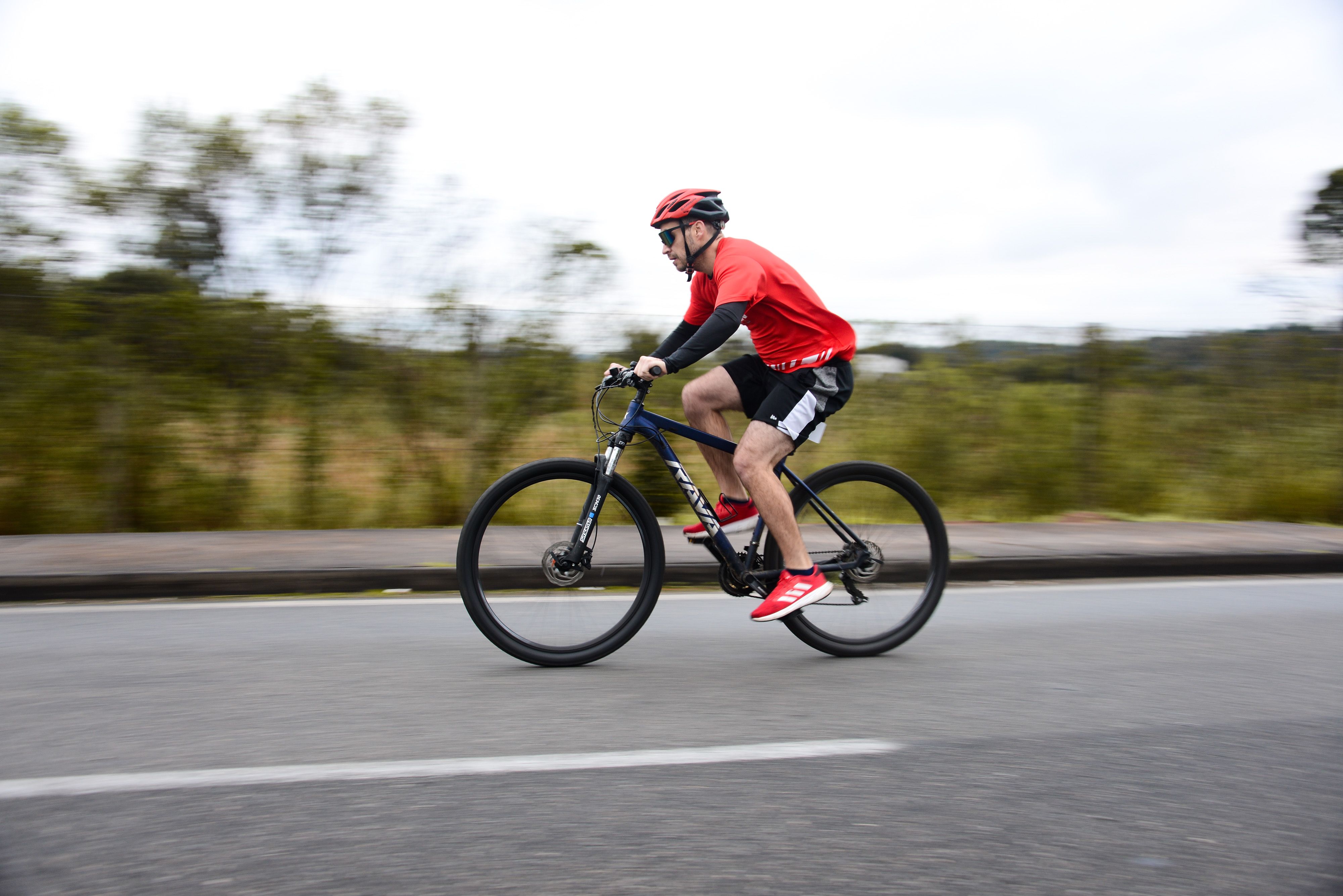 A cyclist in vibrant gear riding through Quatro Barras, Paraná, Brasil during the day.