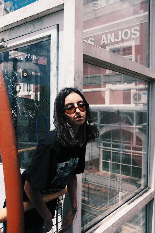 Woman In Black Shirt Standing Beside Glass Window