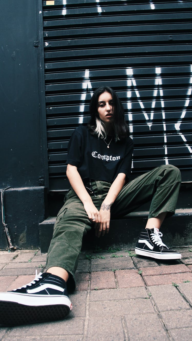 Confident Young Woman Sitting On Street Pavement