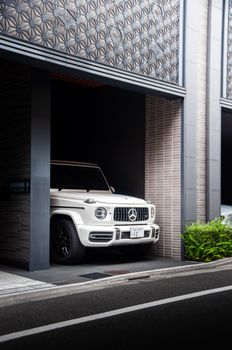 Luxury white SUV parked in a sleek, modern Tokyo building garage, showcasing urban opulence.