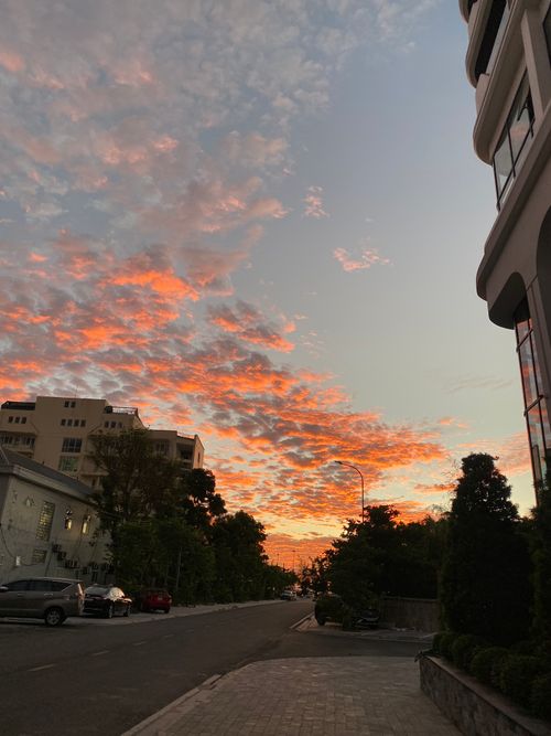 Free A dramatic sunset enhances an urban street with colorful clouds and modern buildings. Stock Photo