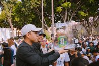 Group of people celebrating with a FIFA World Cup trophy replica in a vibrant outdoor setting.