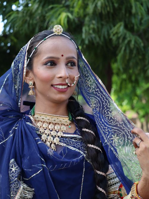 Free Smiling woman in traditional Indian attire with intricate jewelry, outdoors. Stock Photo