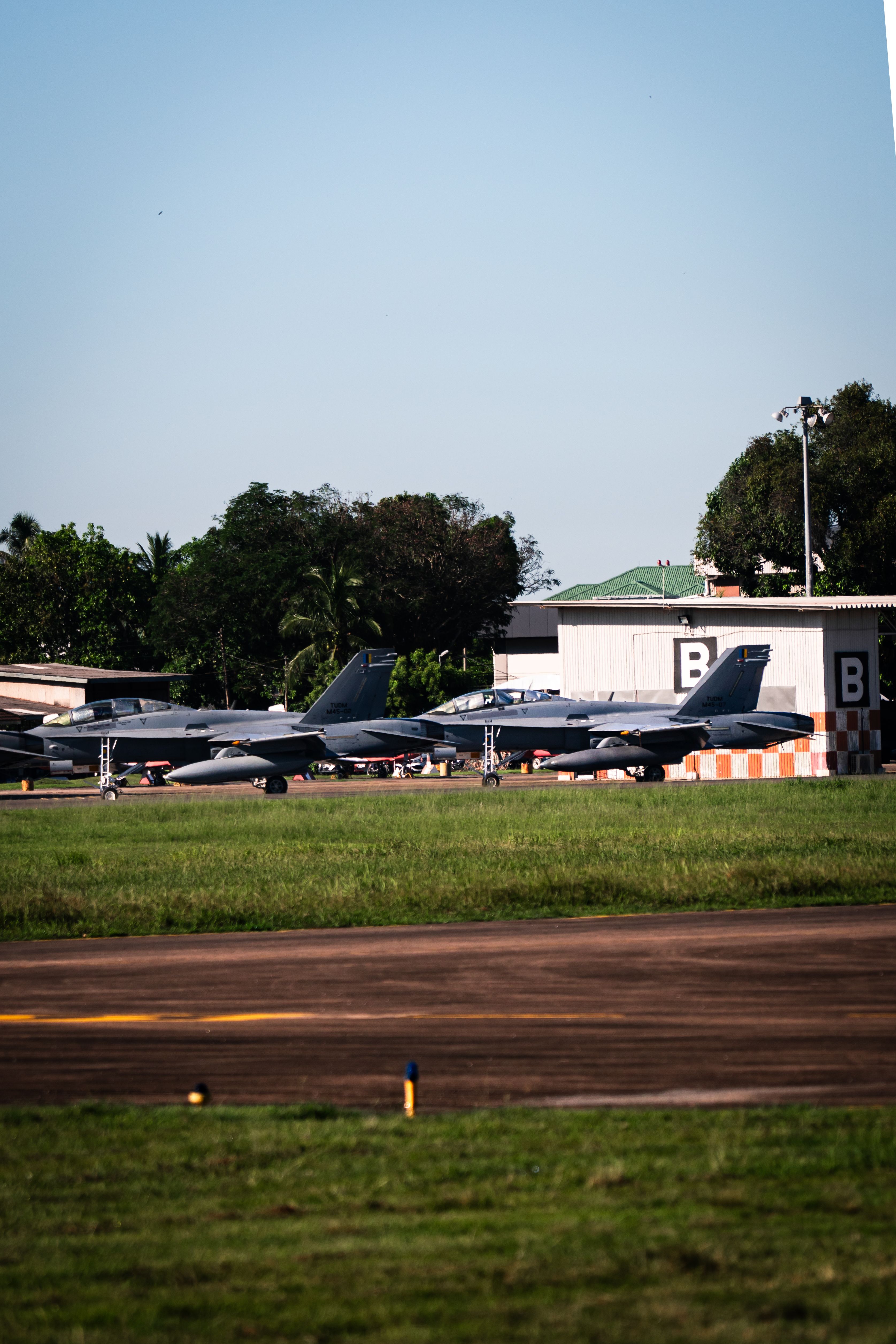 Rij van militaire jets op de startbaan van de luchthaven Alor Setar onder een heldere blauwe lucht.