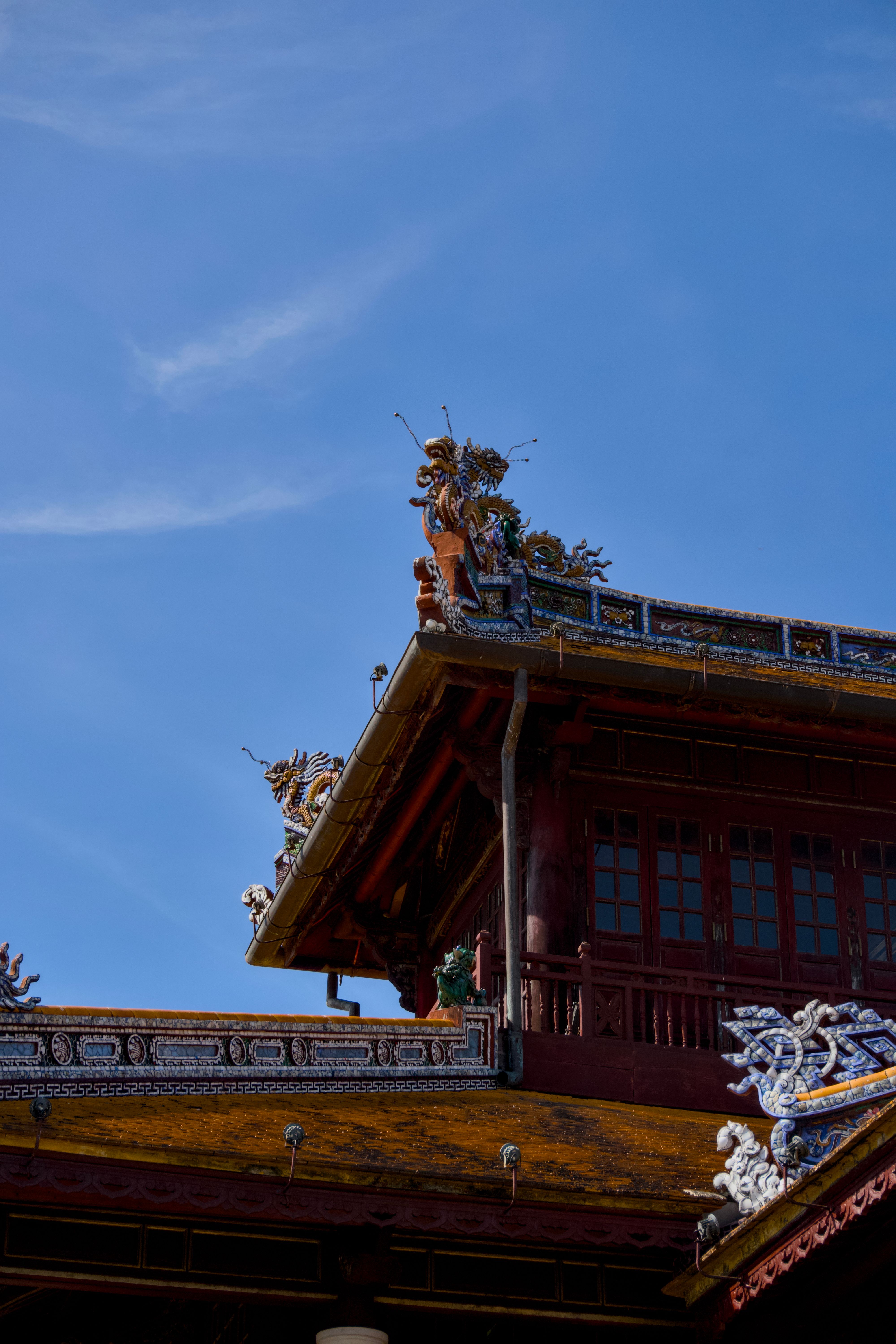 A traditional Asian temple rooftop adorned with intricate dragon designs under a clear blue sky.