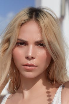 一张年轻金发女子的特写肖像，戴着耳环，表情严肃，背景在户外