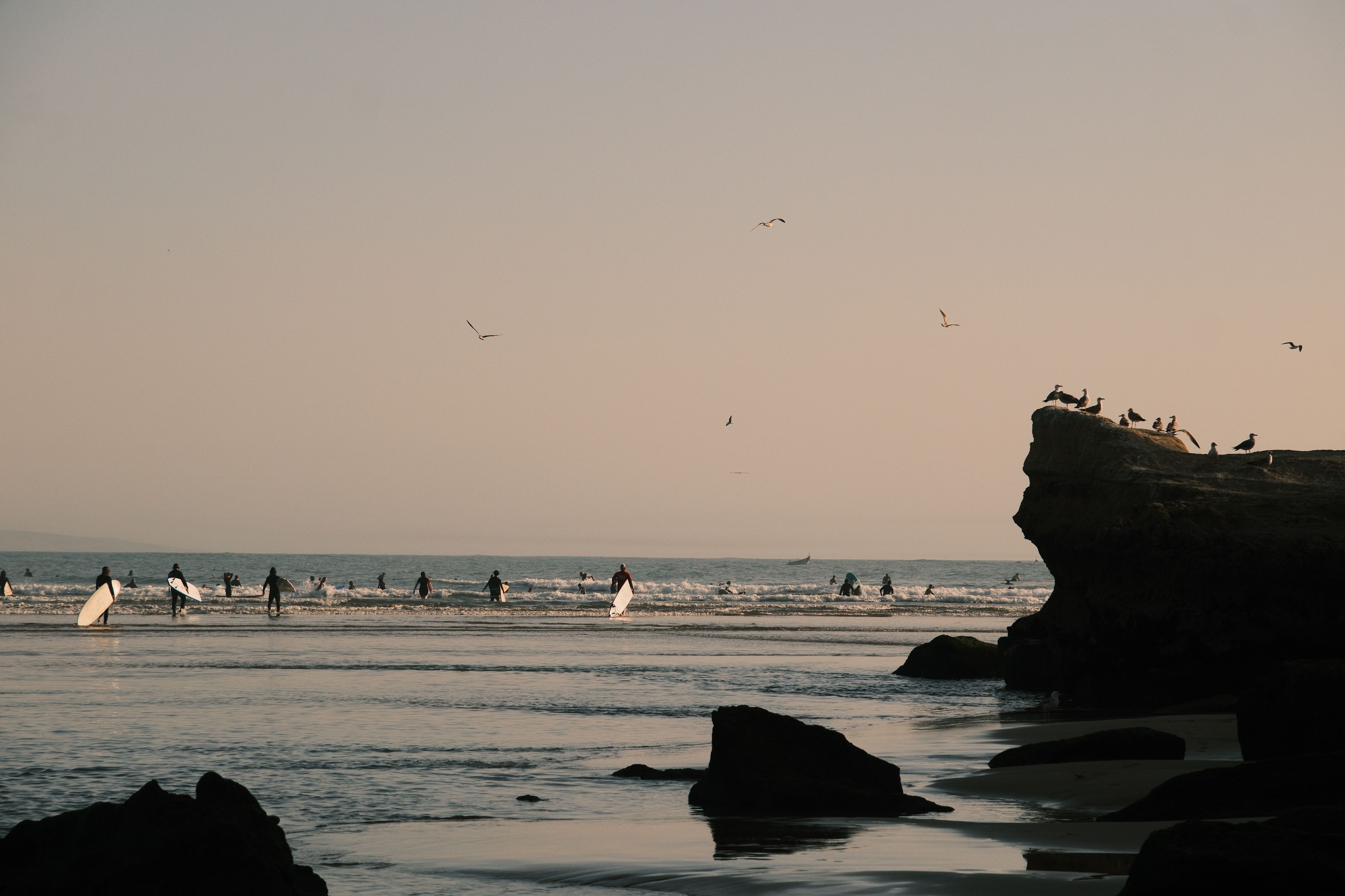 Surfers walking down a cliff path to a reef break north of Ericeira