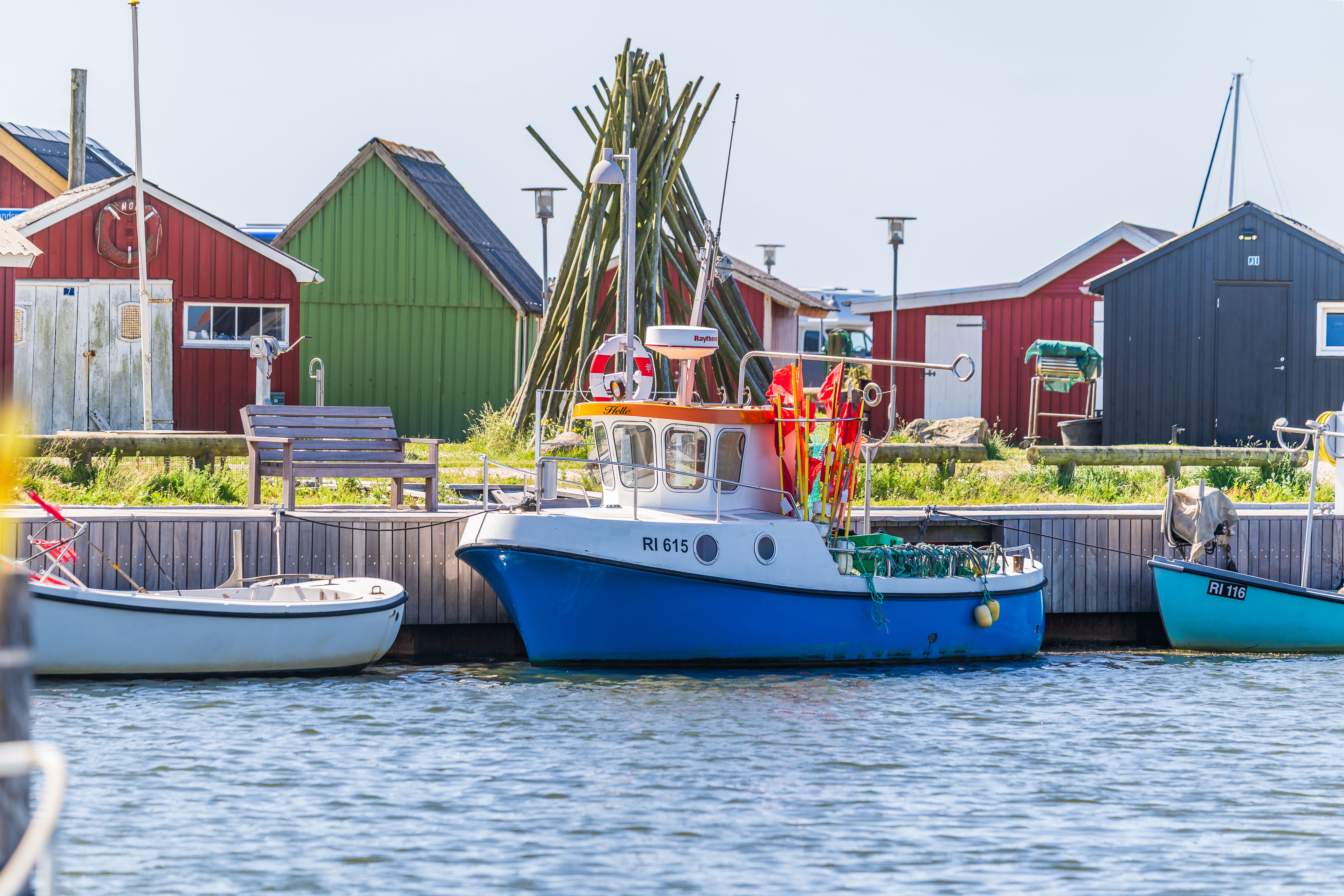 Vibrant fishing boats docked at Ringkøbing harbor with colorful huts in Denmark.