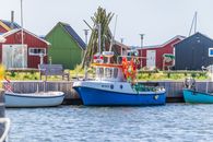 Vibrant fishing boats docked at Ringkøbing harbor with colorful huts in Denmark.