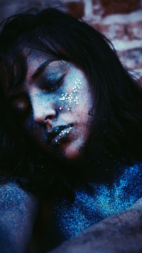 Free Enchanting close-up portrait of a woman adorned with blue glitter, evoking a dreamy fantasy mood. Stock Photo