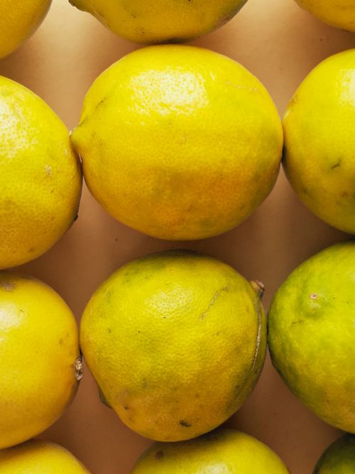 Free Bright yellow and green lemons neatly arranged in rows, displaying vibrant colors and textures. Stock Photo