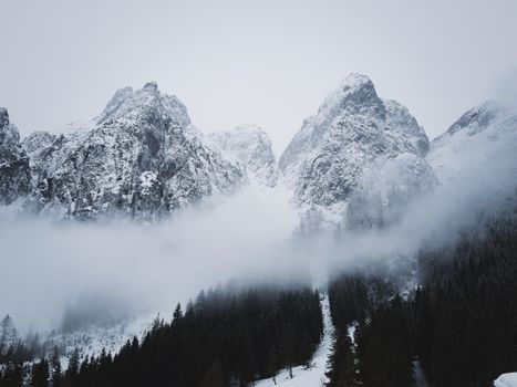 Breathtaking view of fog-covered snow-capped mountains in winter.
