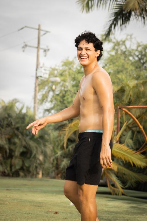 Free A happy young man enjoying a sunny day outdoors, surrounded by greenery. Stock Photo